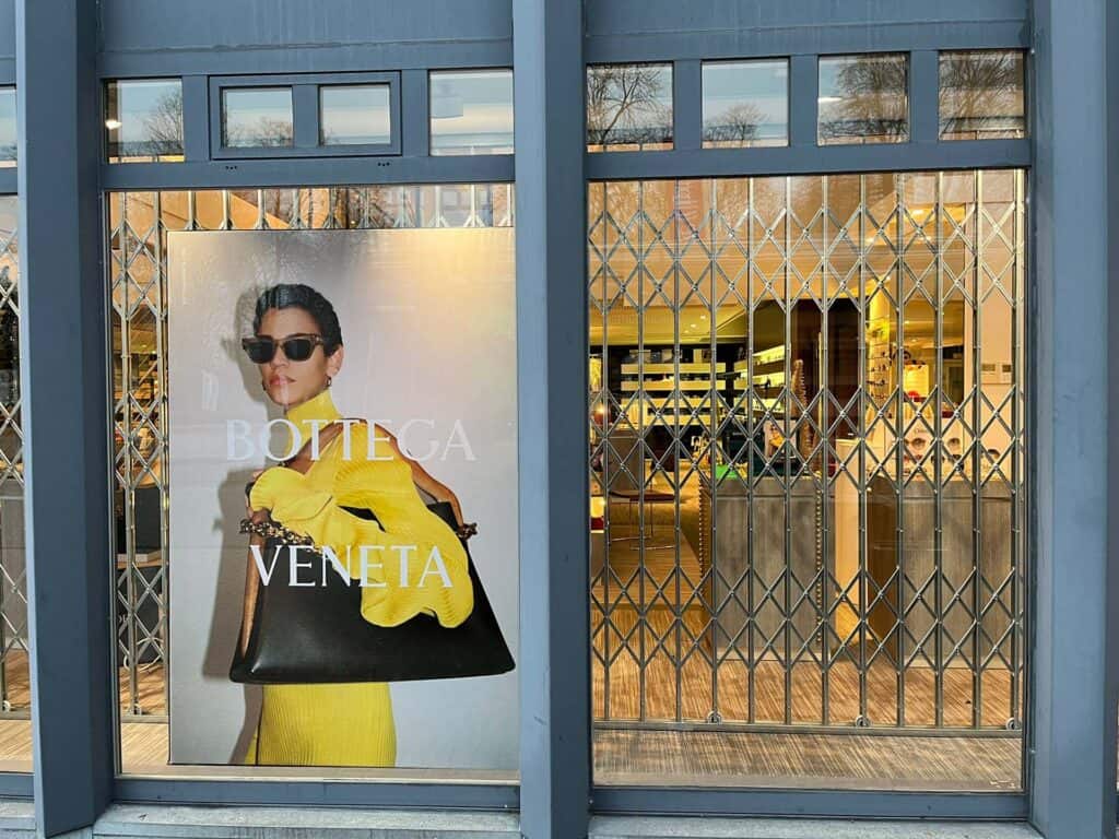 Winkelruit met schaarhekken en Bottega Veneta poster van vrouw met zwarte handtas en zonnebril.