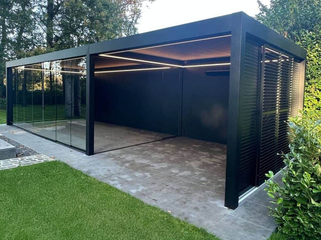 Modern buitenverblijf met zwarte metalen frame, glazen schuifwanden en geïntegreerde verlichting.