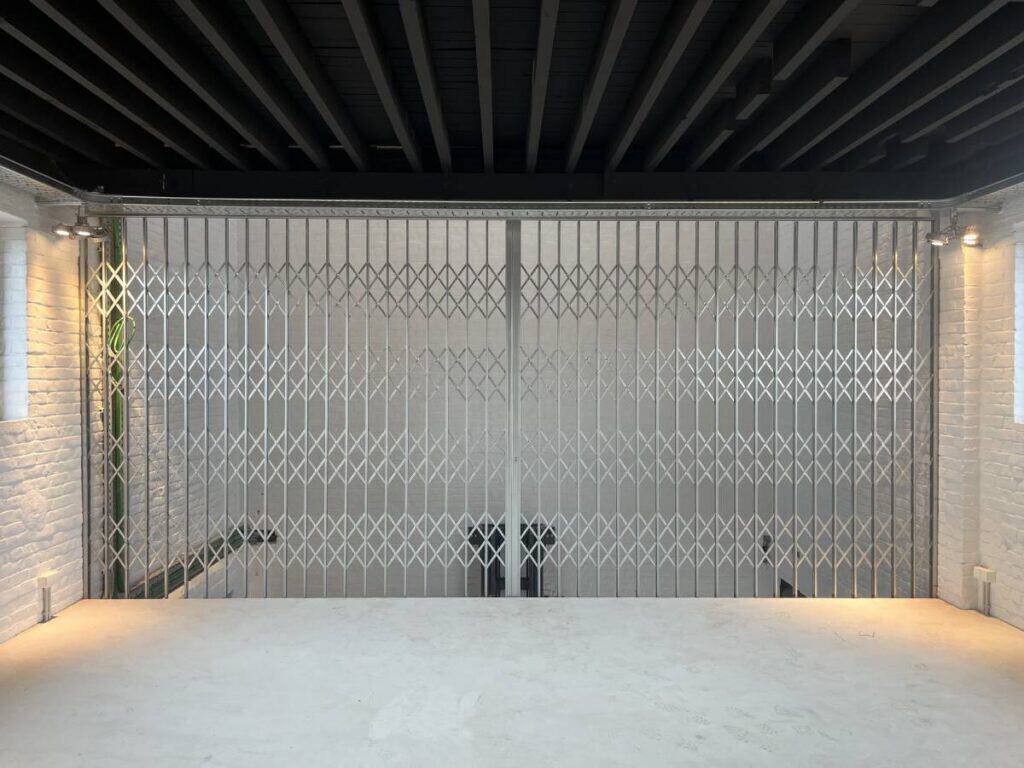 Lege ruimte met witte bakstenen muren, betonnen vloer, zwart plafond en metalen hekken.